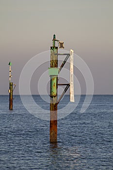 Rusty channel marker in sea with calm water and sky