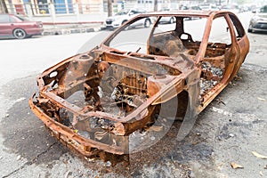 Rusty chassis of a burnt car abandoned by the side of the street