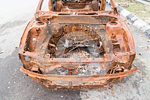 Rusty chassis of a burnt car abandoned by the side of the street