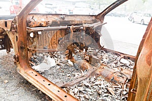 Rusty chassis of a burnt car abandoned by the side of the street