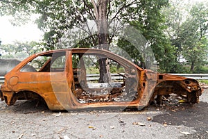 Rusty chassis of a burnt car abandoned by the side of the street