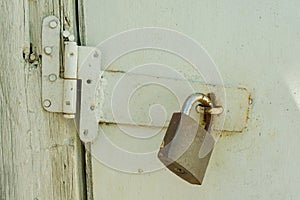 Rusty closed lock on old wooden white cracked painted door