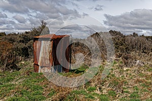 A rusty corrugated iron back country toilet or outhouse