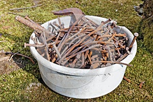 Rusty, curved retro nails are piled in a plastic bowl