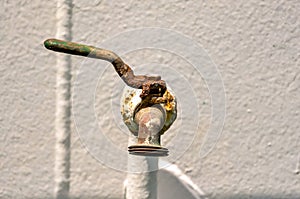 A rusty faucet is sitting on a white wall