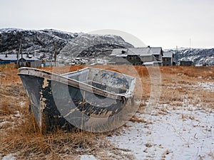 A rusty frozen fishing boat. Old fishing village on the shore of the Barents sea