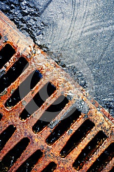 Rusty grate of storm sewers during the rain. Urban drainage system in action. Vertical photo