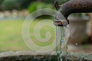 Rusty groundwater metal pipe pumping water