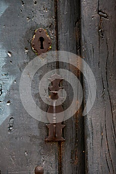 Rusty handle and lock of an old rustic wooden door painted in gray