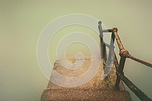 Rusty handrail going down on water with vintage effect
