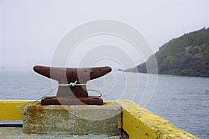 Rusty harbor cleat in foggy Canadian harbor