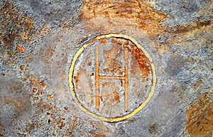 Rusty helipad at abandoned mine over rough stone surface, aerial view directly above