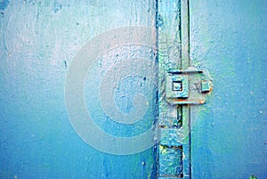 Rusty hinges on old iron door with a shabby turquoise blue, green paint