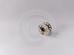 The sewing machine bobbin is rusty. White background.