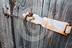 Old and rusty hook locks the old dried up wooden barn door