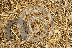 Rusty horseshoes on a straw background - rustic scene in a country style. Old iron Horseshoe - good luck symbol and mascot of well