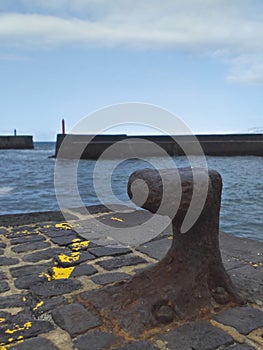 Rusty iron bollard on dock, harbor entrance and port and starboard signals. Nautical, ports and maritime navigation fund