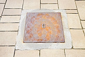 Rusty iron cast manholes in a modern stone paving