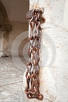 Rusty iron chain on brick wall of historic building