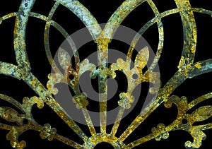 Rusty iron grunge green and yellow lacy metal decoration with fleur-de-lis isolated on black