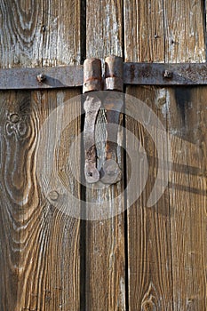 Rusty iron hinges at old wooden barn door