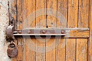 Rusty iron lock on a old wooden door with peeled yellow paint abstract background
