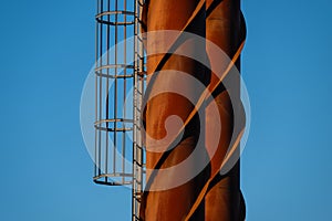 Rusty iron smokestack with ladder..