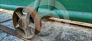 The rusty iron wheel of the old gate of an old abandoned building