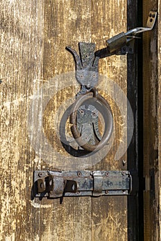 Rusty knocker and bolt on an old wooden door. Old paint and wood texture are visible. Georgia