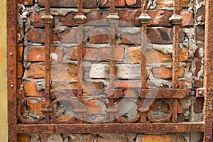 Rusty lattice on the background of an old red brick wall, background or concept