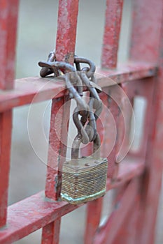 Rusty lock chained to a red gate