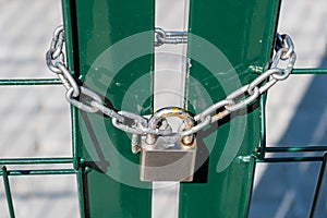 Rusty lock on the gate. Entrance to the football field. Metal fence wire with grass in the background