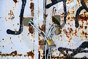 Rusty lock on the gate of a small gray container close-up