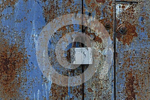 Rusty lock on an old blue metal gate. Close-up