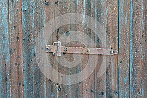 Rusty locking slide latch on frozen wooden old door in the winter