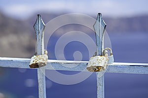 Rusty love padlocks on a fence on a sunny day. Ocean and cliffs in the background