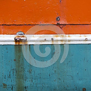 Rusty metal bow of old ship hull in orange blue and white