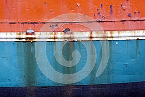 Rusty metal bow of old ship hull in orange blue and white