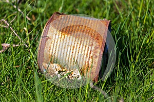 Rusty metal can on the grass in the field