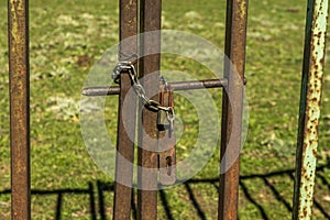 Rusty metal fence of a plot with a chain and a padlock