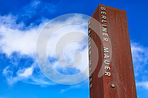 Rusty metal fragment of the Berlin Wall Berliner Mauer in the background of blue sky photo