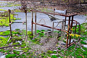 Rusty metal frame of table and chair in schoolyard in dead abandoned ghost town of Pripyat in Chernobyl alienation zone, Ukraine