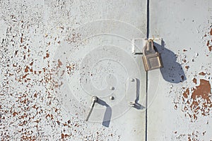 Rusty metal gate with a lock, painted in gray paint.