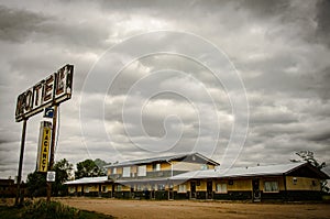 Rusty metal motel sign with wooden old motels under the cloudy and rainy  sky photo