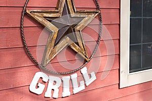 Rusty metal star sign hanging on a wooden wall of a grill place