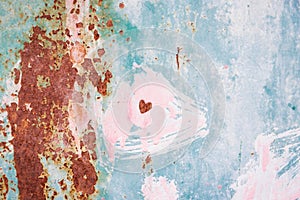 Rusty metal surface with pink, green, blue, turquoise paint flaking. Small heart. Old cracked paint pattern, cracking texture