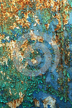 Rusty metal wall, old iron sheet, covered with rust with multi-colored paint. Trace of remnant of old paint in large deep crack on