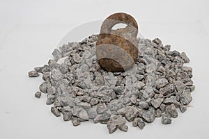 Rusty metal weight placed on crushed granite stones, concept of durability, stability, and strong construction base