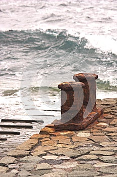 Rusty Noray with ocean waves in the background in a small harbor