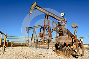 Rusty Oilfield Pumpjack rocking horse over a wellhead. Clear b